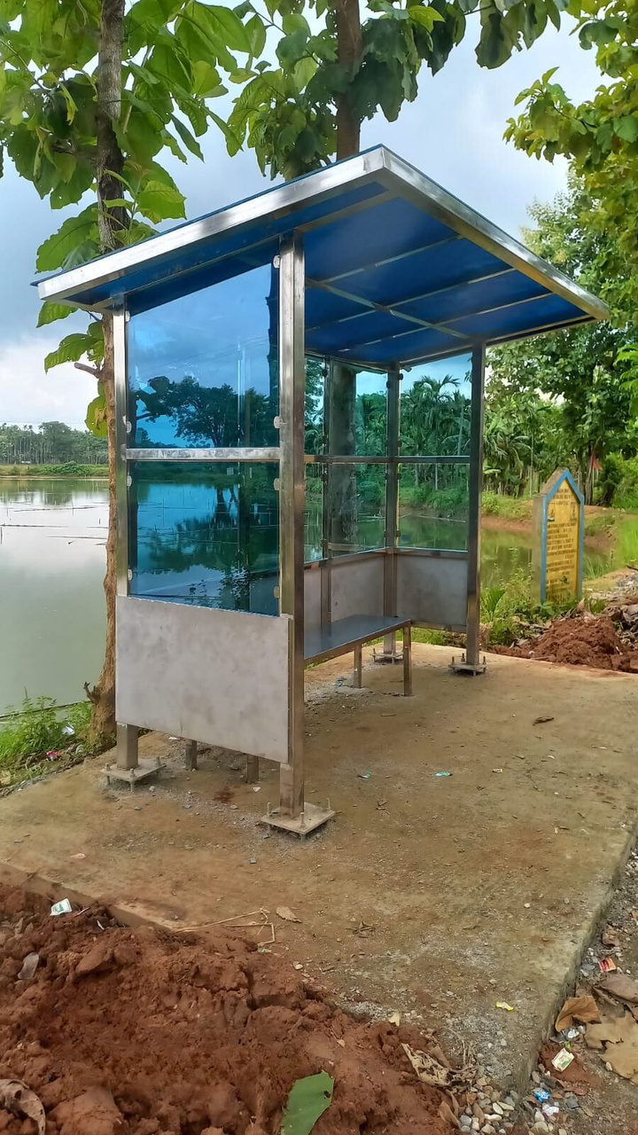 Stainless steel bus shelter beside a pond at Mendipathar